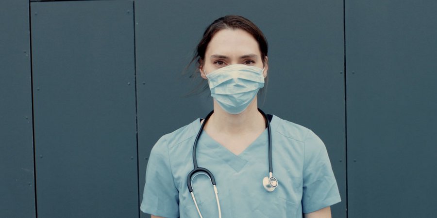 Portrait einer Krankenpflegerin mit Medizinmaske und Stethoskop, das um den Hals gelegt wurde.